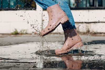 Low section of woman standing on wet glass during rainy season