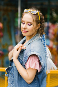 Sensual caucasian woman with blue pigtails and bright makeup in a denim vest in an amusement park