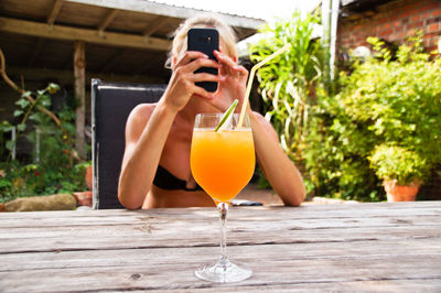 Woman photographing drink on table