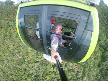 Woman holding monopod while sitting in overhead cable car