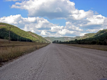 Road leading towards mountains against sky