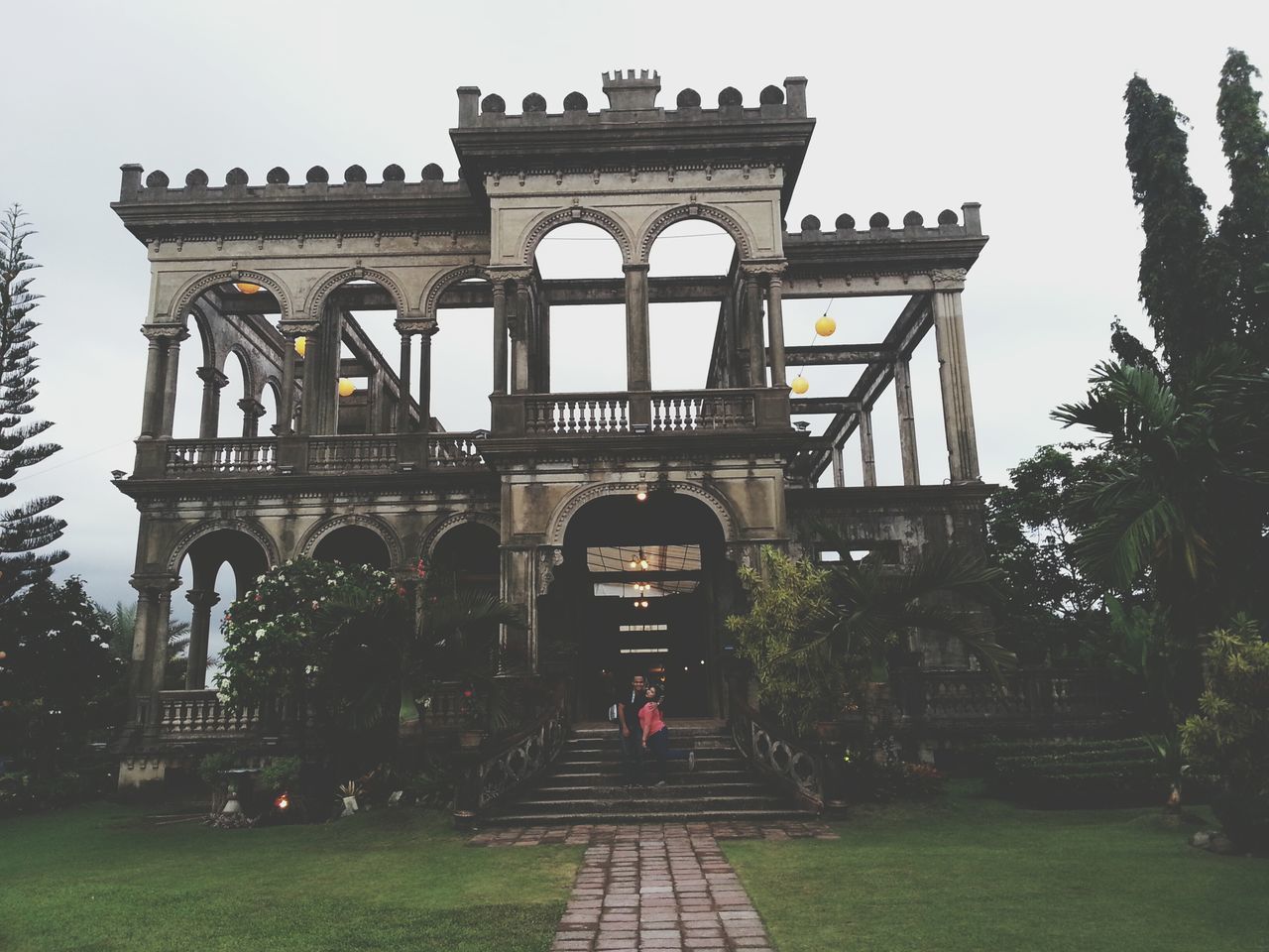 architecture, built structure, tree, building exterior, arch, clear sky, sky, grass, history, outdoors, travel destinations, low angle view, incidental people, day, travel, transportation, gate, famous place, entrance