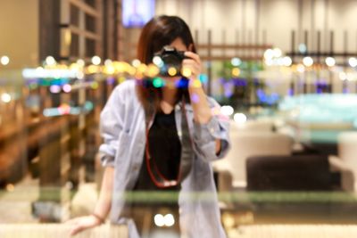 Young woman photographing through smart phone at night