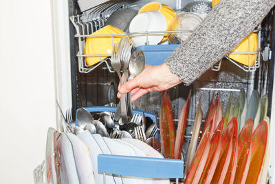 Cropped hand holding spoons at home