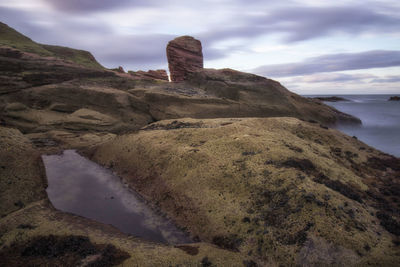 Rock formations by sea against sky