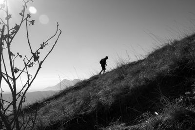 Silhouette man standing on mountain field against clear sky