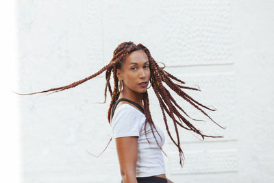 Portrait of young woman standing against white background