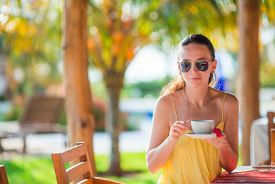 Young woman holding sunglasses at table