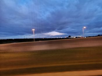 Illuminated street against sky at dusk