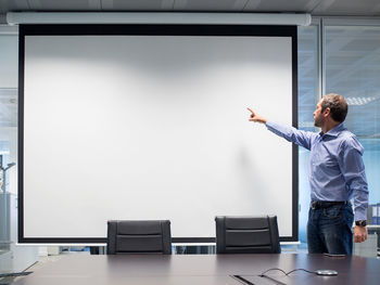 Businessman pointing at projection screen in office