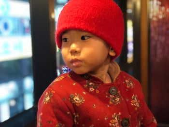 Close-up of cute boy in red traditional clothing sitting at home