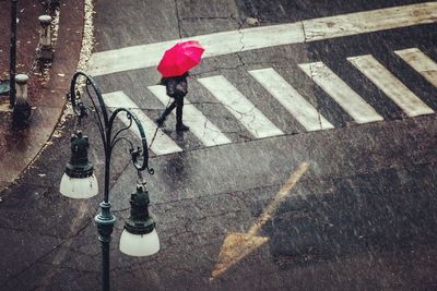High angle view of woman with umbrella walking on road