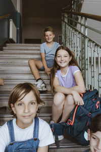 Portrait of male and female school students sitting on staircase