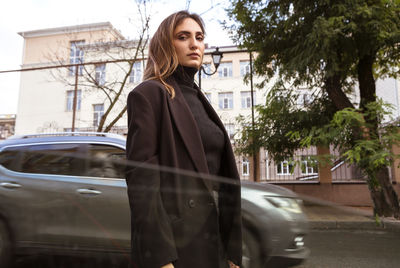 Portrait of young woman standing in city