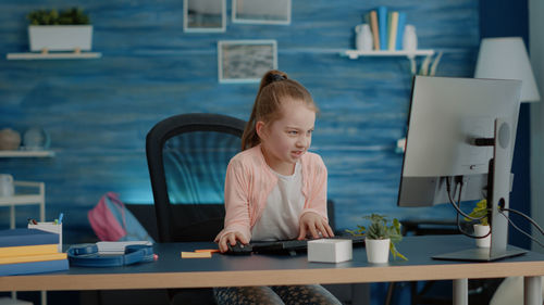 Smiling girl wearing headphones studying online at home