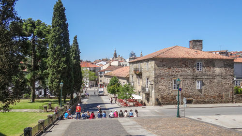 People on road amidst buildings against sky