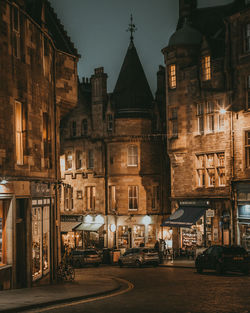 Cars on road by illuminated buildings at night