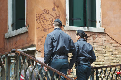 Rear view of man standing on railing against building