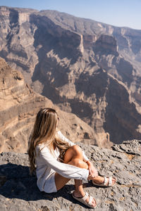 Rear view of woman sitting on mountain