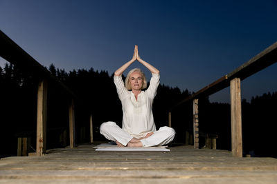 Middle aged woman doing yoga outdoors in forest