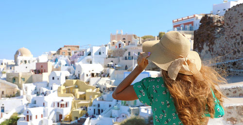 Rear view of woman against buildings in city