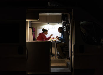 Couple having a relaxed dinner in a motorhome during a trip.