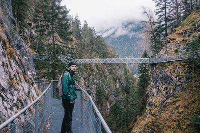 Man standing on footbridge in forest