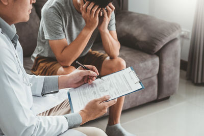 Midsection of man using mobile phone while sitting on sofa