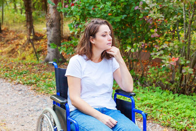 Young woman using mobile phone while sitting in park