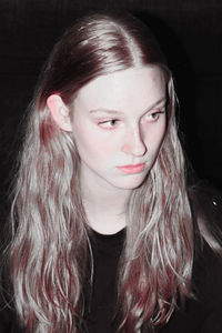 Close-up of beautiful young woman against black background