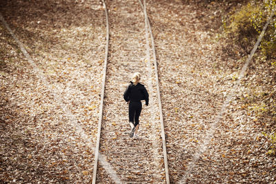 High angle view of woman jogging on railroad track during autumn