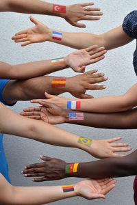 Cropped hands of people with flags on hand against wall