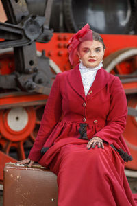 Portrait of young woman sitting on suitcase