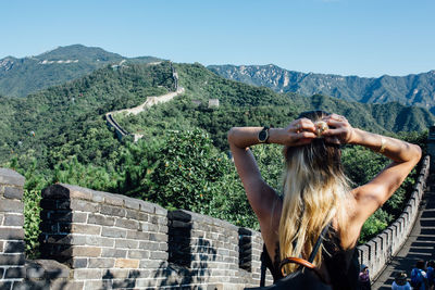 Rear view of woman tying hair while standing at great wall of china