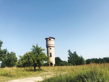 Water tower on field against clear blue sky