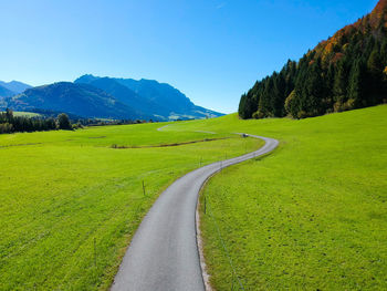 Scenic view of road amidst field against sky