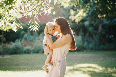 Mother and boy standing by tree at park