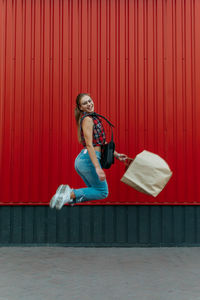 Woman sitting on red wall