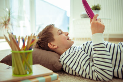 Boy using digital tablet while lying at home