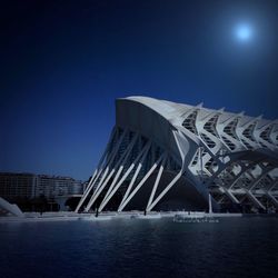 Modern bridge over river against blue sky at night