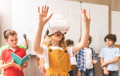 Cute girl using virtual reality simulator at classroom