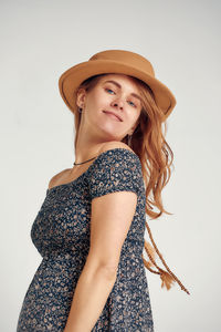 Portrait of young woman standing against white background