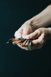 Hand holding paintbrush against black background