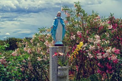 Man standing by statue against trees