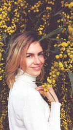 Close-up portrait of woman smiling while standing amidst yellow flowers