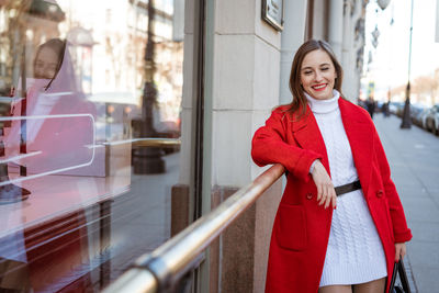 A young woman in a red coat near a shop window