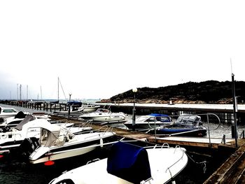 Boats moored at harbor against clear sky