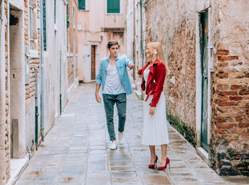 Full length of couple walking in alley against buildings