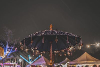 Low angle view of umbrella against sky during snowfall at night