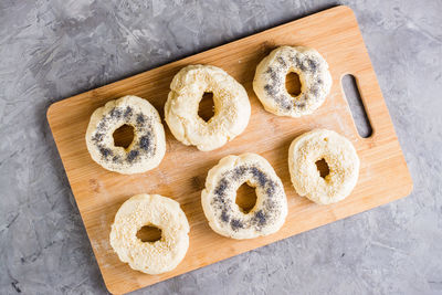 Raw bagels with poppy seeds and sesame seeds on a board on the table. homemade pastries. top view